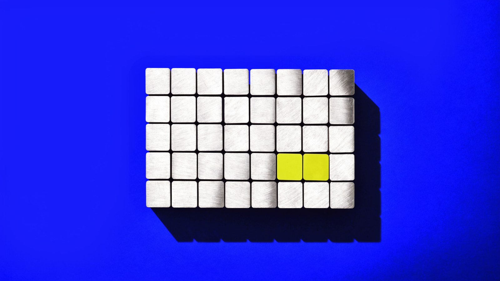 A grid of brushed metal tiles on cobalt, two of them chartreuse