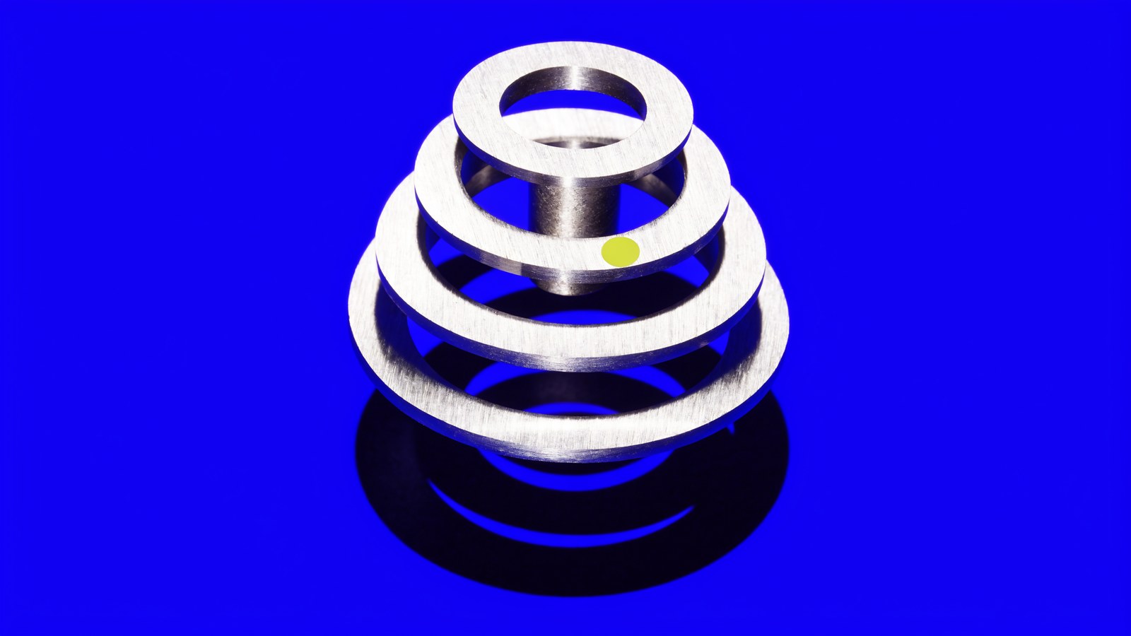 Stacked machined steel rings on cobalt with a chartreuse mark